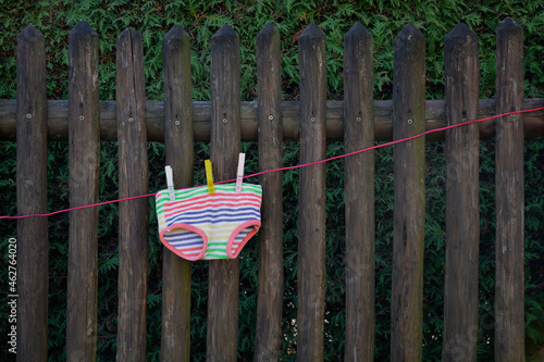 Colorful underpants drying on clothesline in front of wooden fence photo