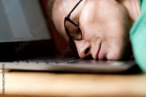 Tred mature woman sleeping on laptop at home during curfew photo