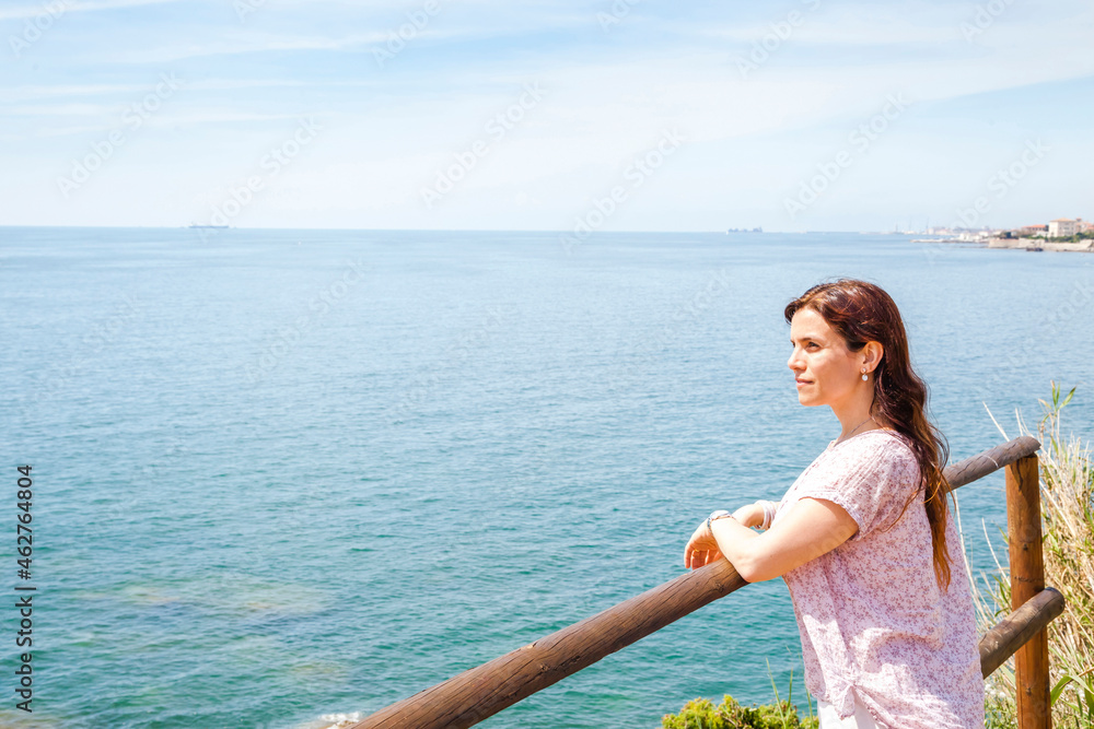 Woman leaning on railing while looking at Ligurian Sea against sky during sunny day Woman leaning on railing while looking at Ligurian Sea against sky during sunny day