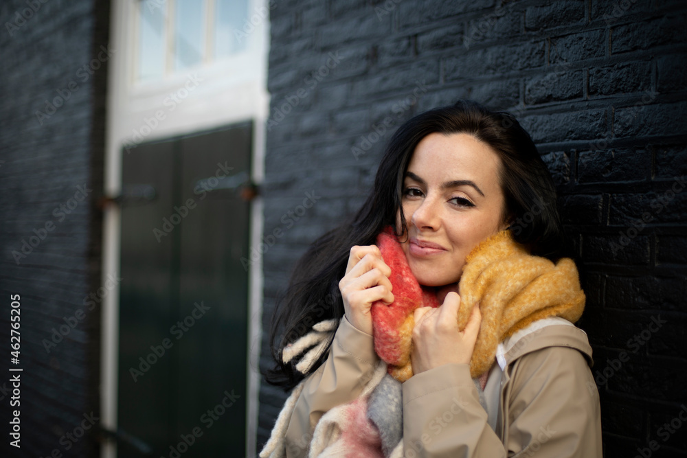 Beautiful woman in warm clothing against black brick wall during winter Beautiful woman in warm clothing against black brick wall during winter
