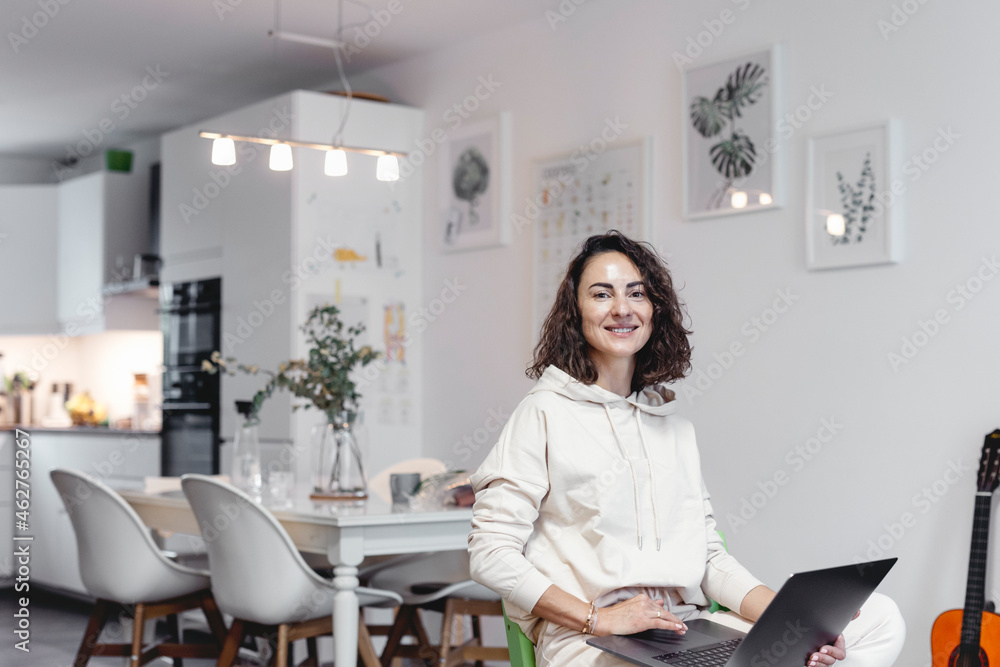 Portrait of smiling woman with laptop at home Portrait of smiling woman with laptop at home