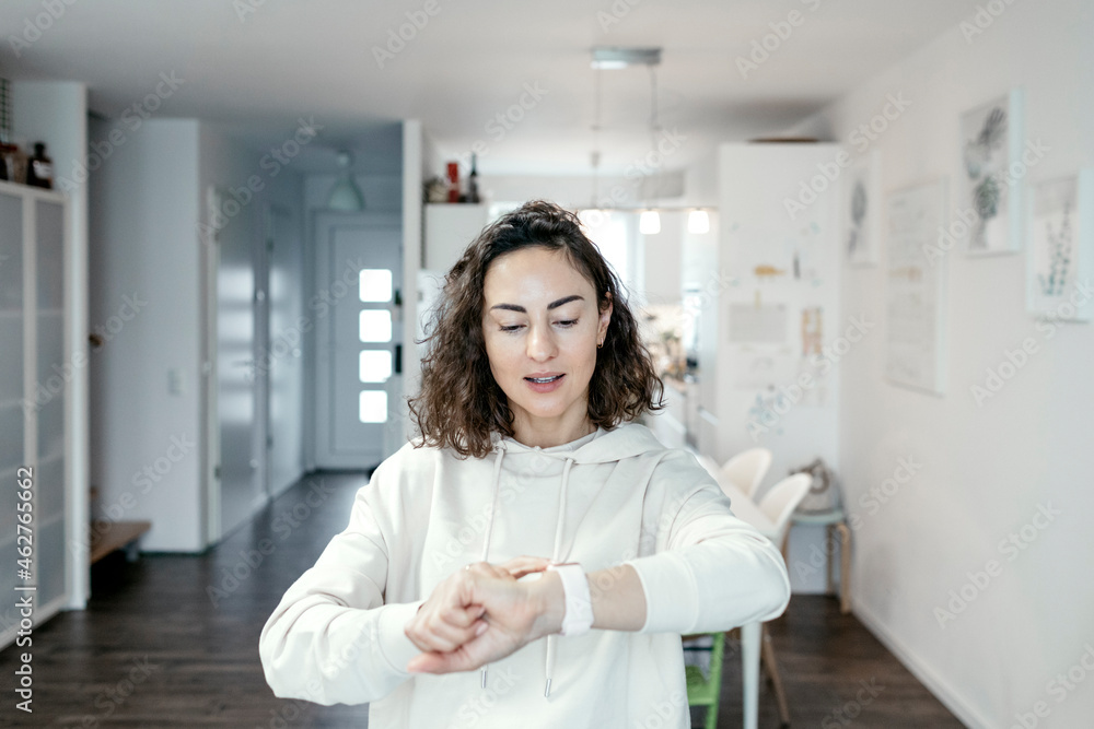 Portrait of woman looking at her smartwatch at home Portrait of woman looking at her smartwatch at home