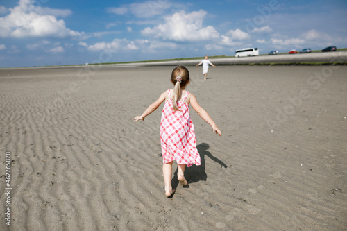 Back view of little girl running on the beach, Bergen op Zoom, Netherlands photo