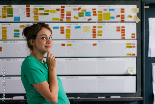 Portrait of smiling pregnant woman working on schedule in office