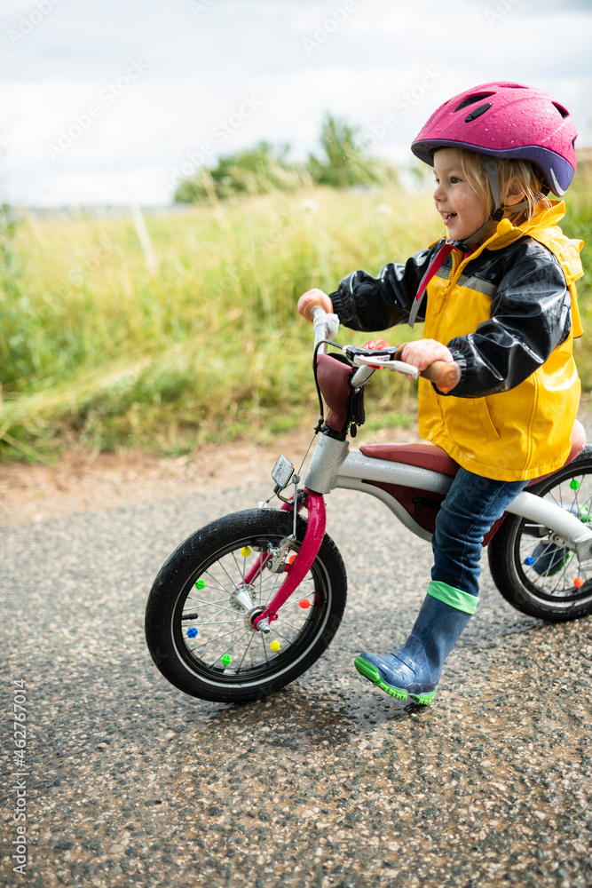 Toddler girl with pink cycling helmet on balance bicycle Toddler girl with pink cycling helmet on balance bicycle
