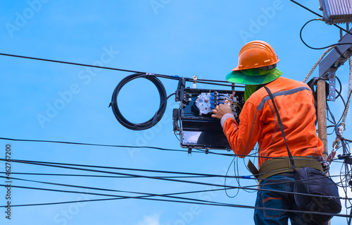 фотографія Rear view of technician on wooden ladder checking code numbers of  fiber optic c
