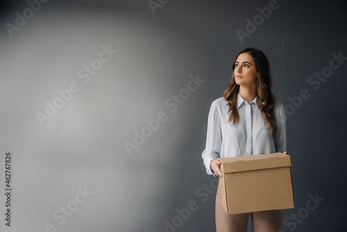 Serious young businesswoman holding cardboard box photo