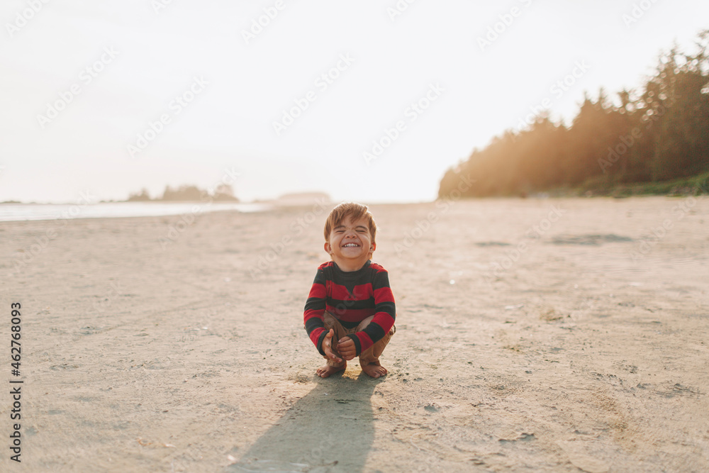 Cute boy crouching while playing on sand at beach Cute boy crouching while playing on sand at beach