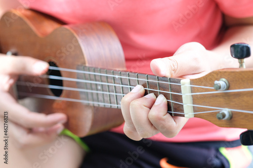 Beautiful face girl She is playing a brown ukulele at the park on her vacation weekend.soft focus