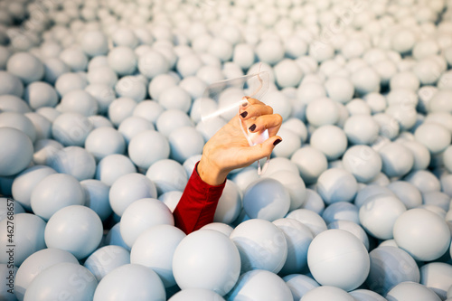 Hand of young woman holding face shield in ball pit photo