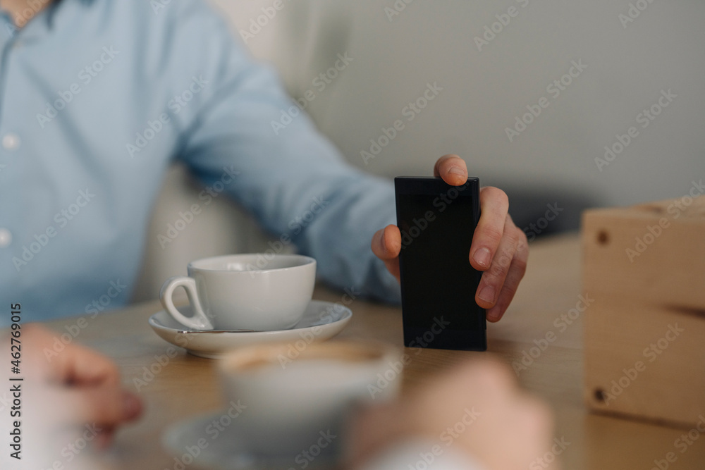 Two businessmen having a meeting, close up of hand, holding smartphone Two businessmen having a meeting, close up of hand, holding smartphone
