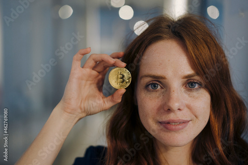 Portrait of redheaded woman holding bitcoin photo