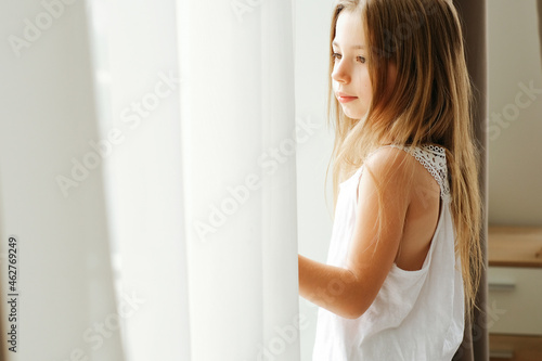 Little girl with long hair by the window