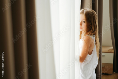 Little girl with long hair by the window