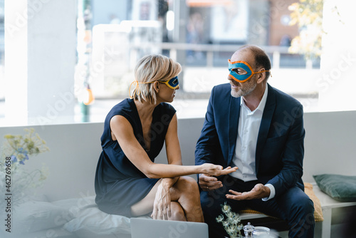 Businessman and woman wearing super hero masks, trying to find solutions photo