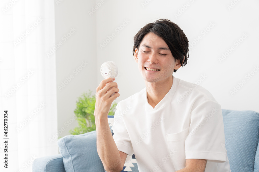 ハンディ扇風機で涼む若い男性・熱中症対策
