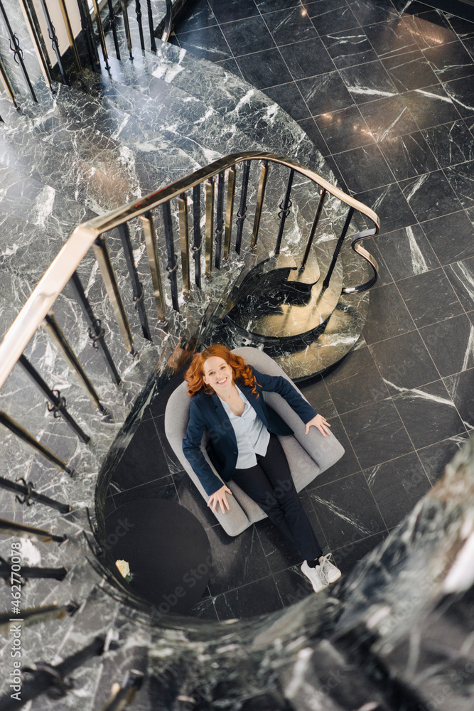 Top view of businesswoman sitting in armchair at staircase Top view of businesswoman sitting in armchair at staircase