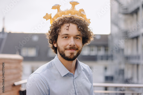 Portrait of confident businessman on roof terrace wearing a crown photo