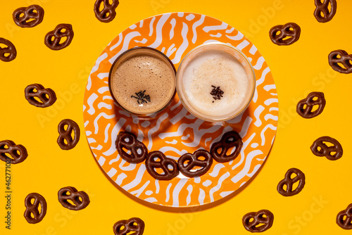 Anthropomorphic face made of plate, chocolate pretzels and two glasses of coffee photo