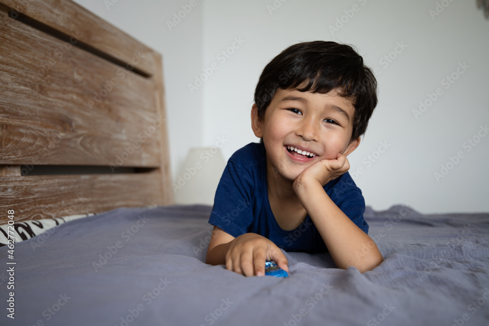 Portrait of cute asian boy lies on the bed and looking at camera Portrait of cute asian boy lies on the bed and looking at camera