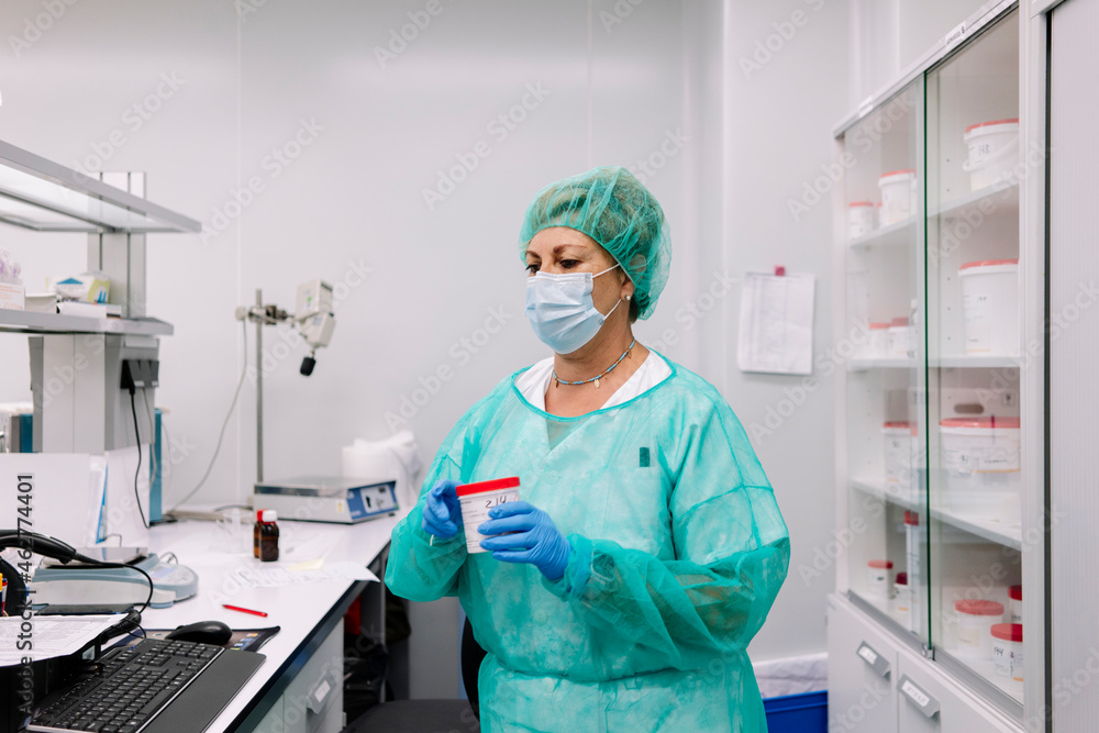 Female pharmacist holding medicine bottle while standing in laboratory Female pharmacist holding medicine bottle while standing in laboratory
