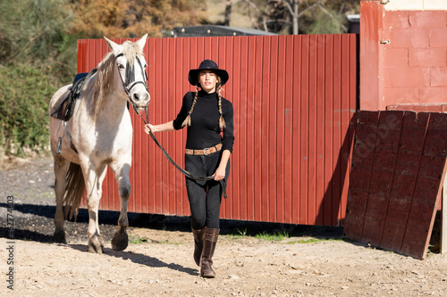 Woman walking with horse in paddock