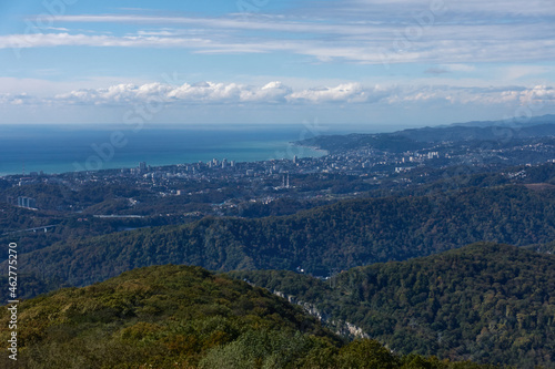 View of the city located between the sea and the mountains. Above are cumulus clouds  a mountain forest and poles with electrical wires.