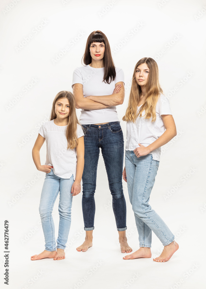 Confident mother with arms crossed standing by daughter in studio Confident mother with arms crossed standing by daughter in studio