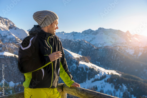 Man standing by railing while looking at snowcapped mountains against sky photo