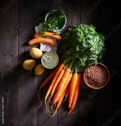 Bunch of carrots, sausages, parsley, potatoes, canned lentil soup and bowl of lentils photo