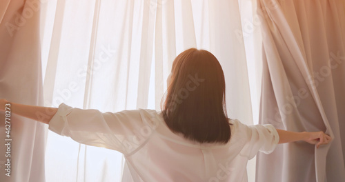 woman opens curtain