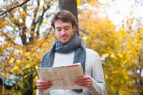 Portrait of young man reading newspaper outdoors photo