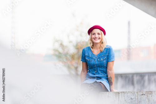 Portrait of happy young woman wearing denim dress sitting on a wall photo