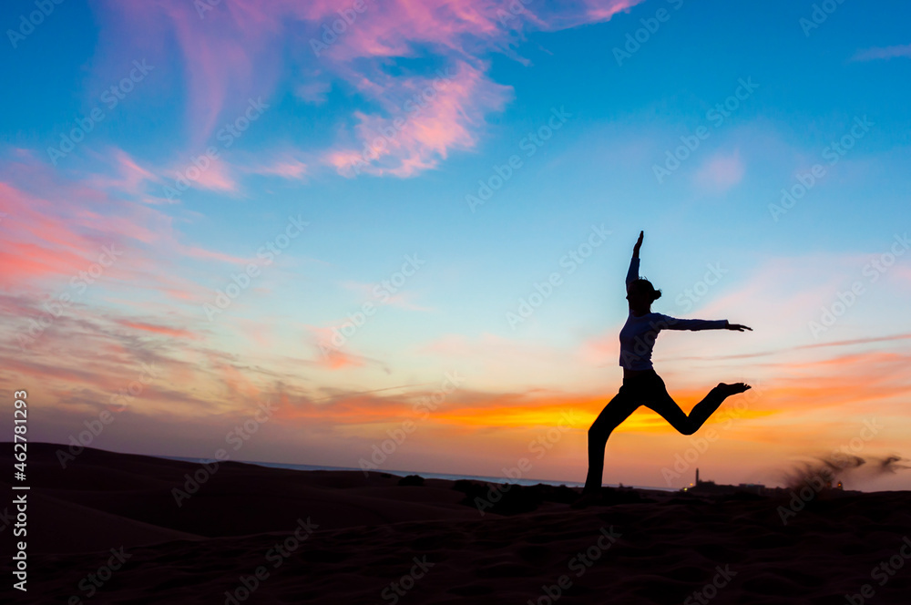 Silhouette of woman jumping at sunset in the dunes, Gran Canaria, Spain Silhouette of woman jumping at sunset in the dunes, Gran Canaria, Spain