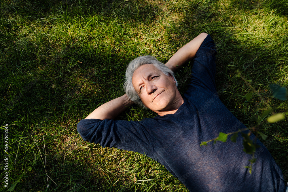 Confident smiling man lying down in field Confident smiling man lying down in field