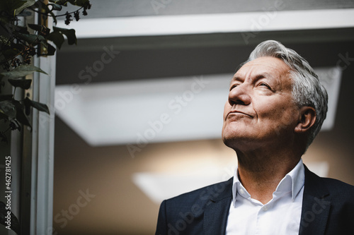 Successful businessman looking up in satisfaction