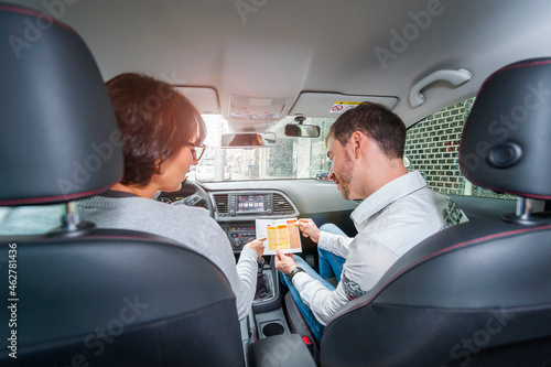 Female learner driver with instructor in car looking at test script