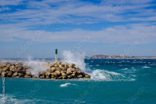 France, Marseille, Place Florence Arthaud, La Madrague, strong waves at a jetty with lighthouse photo