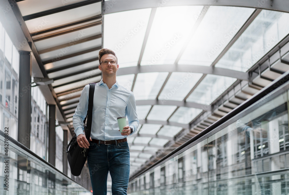 Businessman with coffee cup looking away in city Businessman with coffee cup looking away in city