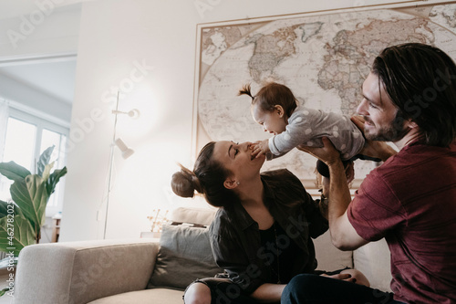 Happy family playing with baby girl in living room at home