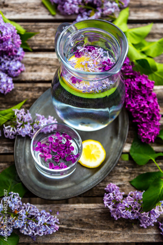 Jar with glass of water with lilac sirup and lemon photo