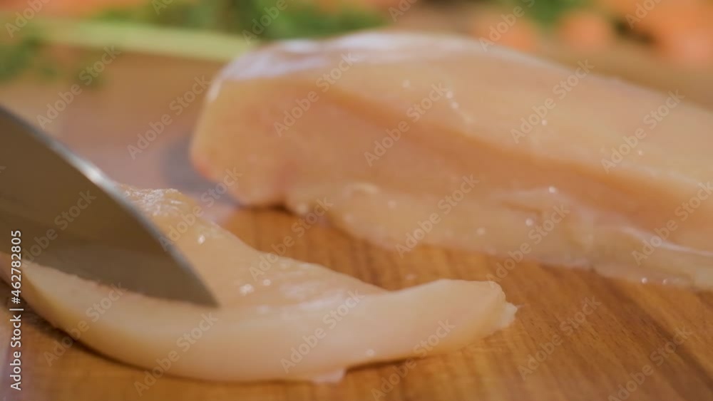 Knife Slicing Chicken Breast Fillet On Wooden Chopping Board. - close up, slow motion Knife Slicing Chicken Breast Fillet On Wooden Chopping Board. - close up, slow motion
