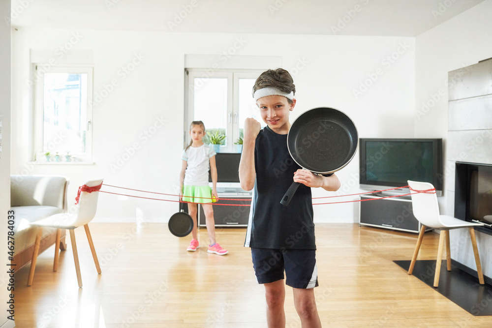 Boy winning while playing tennis with sister in living room at home Boy winning while playing tennis with sister in living room at home