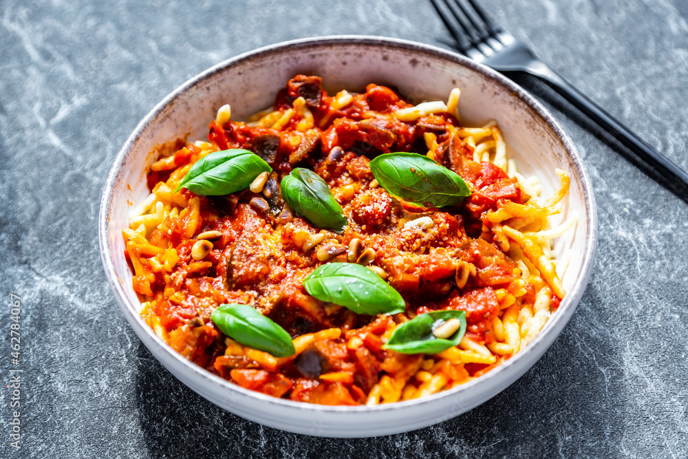 Bowl of pasta with aubergine tomato sugo garnished with pine nuts, parmesan and basil Bowl of pasta with aubergine tomato sugo garnished with pine nuts, parmesan and basil