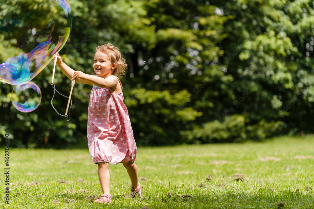 Smiling girl running with bubble wand at park Smiling girl running with bubble wand at park