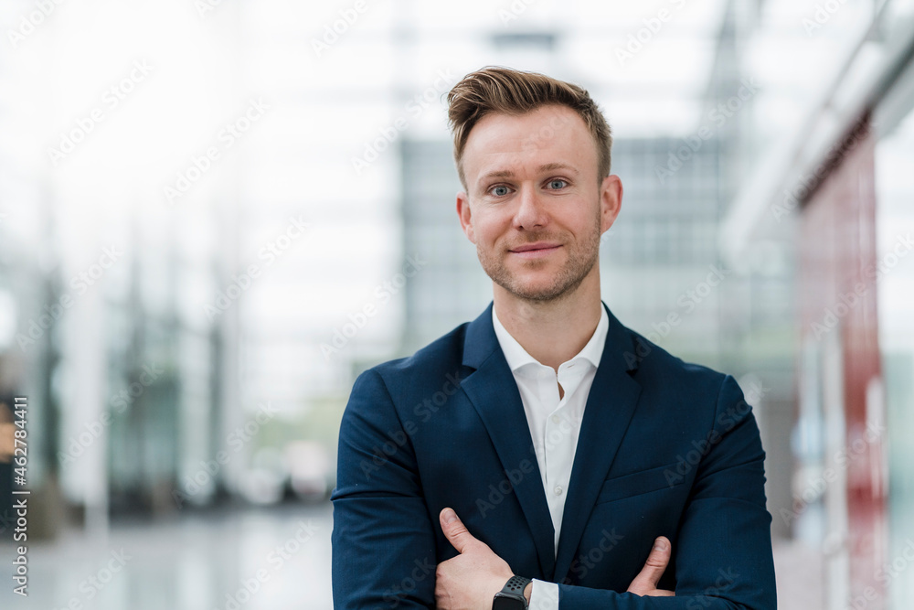 Smiling businessman with arms crossed standing in city Smiling businessman with arms crossed standing in city