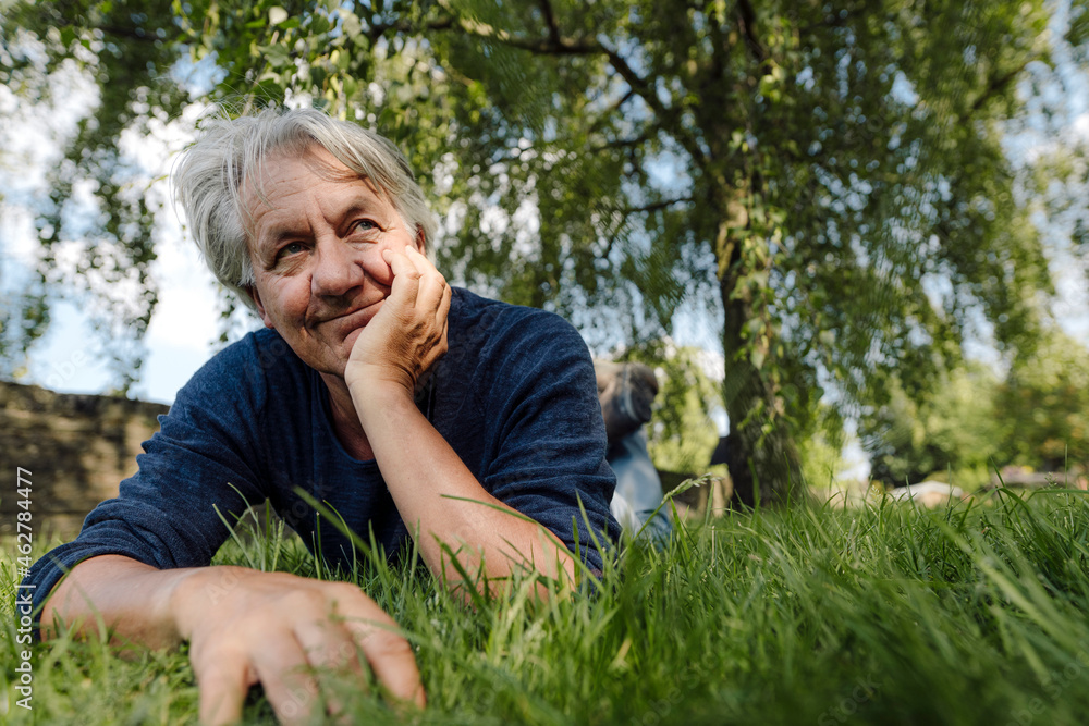 Confident smiling man lying on front in field Confident smiling man lying on front in field