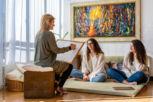 Female psychologist talking to patients while writing on slate while counseling in office