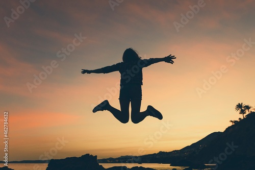 Silhouette of jumping woman at beach during sunset photo