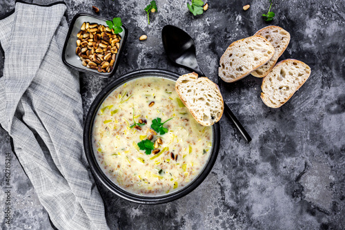 Bowl of vegetarian leek soup with cheese, pine nuts and parsley photo